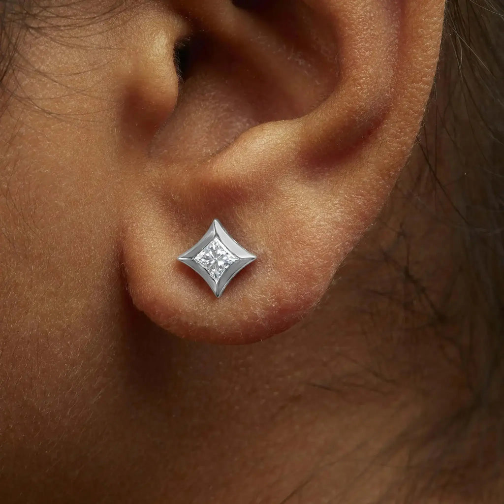 10K white gold princess-cut diamond stud earrings with invisible setting on ear.
